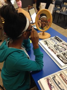 A student tries on frames received through the Illinois Eye Institute at Princeton Elementary.