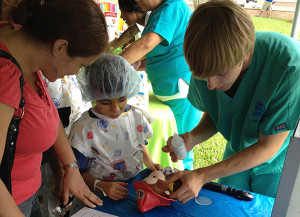 A young “doctor” dilates Curious George’s eyes with the help of his mother and second-year NOVA optometry student Danny Hamilton.